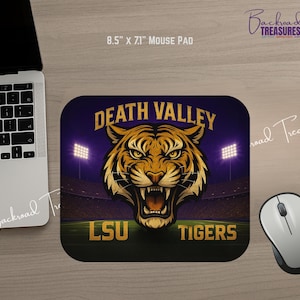 May include: A rectangular mouse pad with a graphic of a tiger's head, the words "DEATH VALLEY" and "LSU TIGERS". The mouse pad measures 8.5 x 7.1 inches. The background is a stadium with lights.