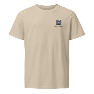 Könnte beinhalten: Beiges T-Shirt mit einer kleinen Grafik einer Diskette und dem Text "I was there!". Das Shirt hat einen Rundhalsausschnitt und kurze Ärmel. Ein schlichtes, lässiges Design.