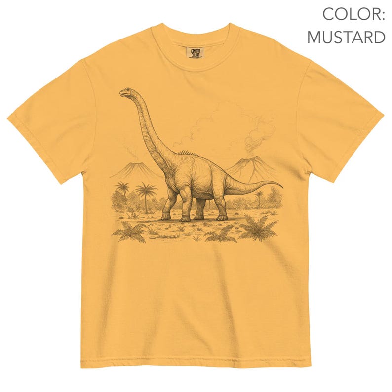 Pu&ograve; includere: T-shirt color senape con un'illustrazione dettagliata di un dinosauro Brachiosaurus in un paesaggio preistorico. Il design include palme, vulcani e una rappresentazione dettagliata del dinosauro.