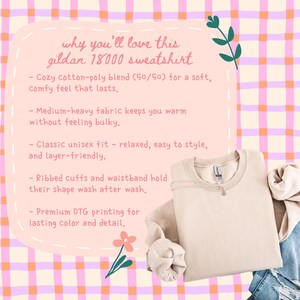 Puede incluir: Una sudadera beige Gildan 18000 doblada, con cuello redondo y pu&ntilde;os acanalados. La imagen incluye texto que describe las caracter&iacute;sticas de la sudadera, como su mezcla de algod&oacute;n y poli&eacute;ster y su ajuste unisex. El fondo es un patr&oacute;n de cuadros rosa y naranja.