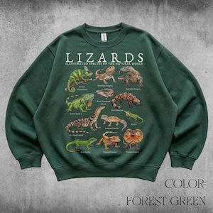 Könnte beinhalten: Ein waldgrünes Sweatshirt mit Rundhalsausschnitt und einem Grafikdruck mit dem Titel LIZARDS ILLUSTRATED SPECIES OF THE NATURAL WORLD. Das Design zeigt detaillierte Illustrationen verschiedener Echsenarten mit ihren Namen in weiß.