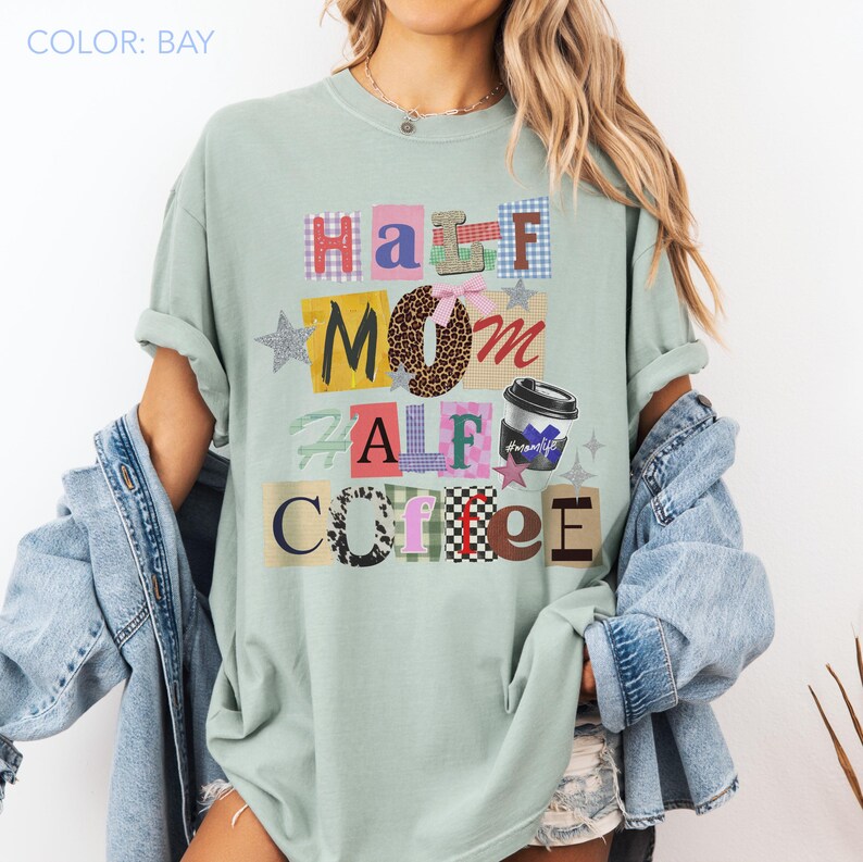 May include: A light green t-shirt with the words "Half Mom Half Coffee" in a collage style. The design includes a coffee cup graphic and star accents. The shirt is a relaxed fit.
