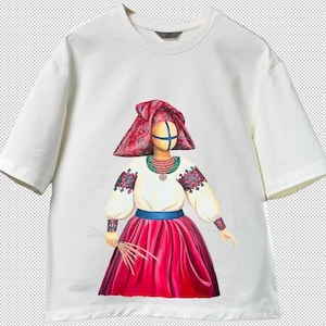 Peut inclure: T-shirt blanc avec une illustration colorée d'une figure en costume traditionnel ukrainien. La figure porte un couvre-chef rouge, une blouse blanche à manches brodées et une jupe rouge. La figure tient du blé.