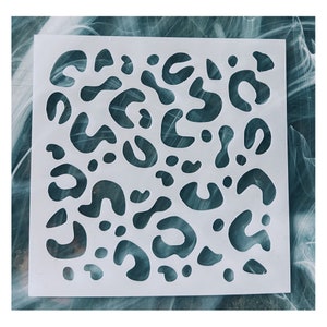 May include: White plastic stencil with a leopard print design. The stencil is made of a thin, flexible plastic and has a variety of sizes and shapes of leopard spots.