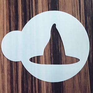 May include: A white plastic stencil featuring a witch's hat design. The stencil is circular with a smaller, attached circular shape. The hat is a classic pointed shape, perfect for Halloween-themed crafts and decorations.