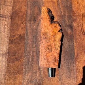 May include: A wooden beer tap handle with a natural wood finish and a metal spigot. The handle has a unique, irregular shape and a natural wood grain pattern.
