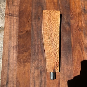May include: A wooden beer tap handle with a natural wood finish. The handle is made of a light brown wood with a darker brown grain pattern. The handle is about 10 inches long and 2 inches wide.