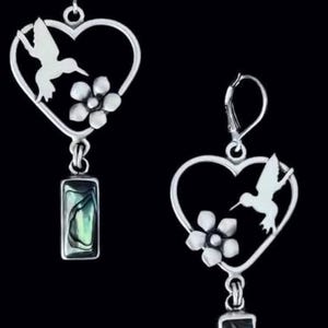 Può includere: Un paio di orecchini pendenti color argento con una cornice a cuore aperta, un colibrì ritagliato e un fiore a cinque petali. Un ciondolo rettangolare con un intarsio in conchiglia di abalone iridescente pende da ogni cuore.