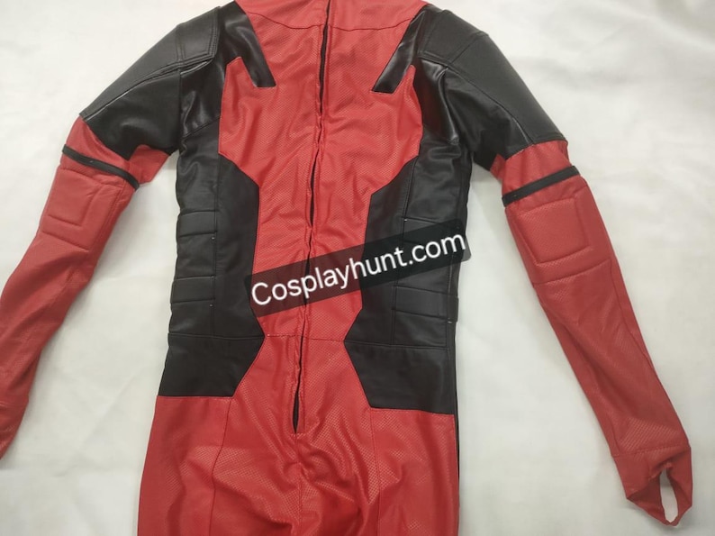 Pu&ograve; includere: Tuta rossa e nera con cerniera a tutta lunghezza. Il costume presenta pannelli neri sulle spalle, sul petto e sui lati, con dettagli imbottiti su braccia e gambe. Il testo "Cosplayhunt.com" &egrave; visibile.