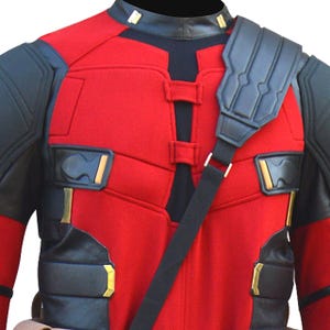 May include: Red and black costume with a black shoulder strap. The costume has a red torso with black accents on the shoulders, arms, and chest. Gold-colored details are visible on the chest and shoulders. The costume has a black collar.