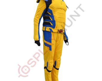 Può includere: Un costume da supereroe giallo e blu con petto e spalle imbottite. Il costume presenta accenti blu su braccia, gambe e busto, con una cintura rossa e dorata. L'outfit è progettato per assomigliare a un personaggio dei fumetti.