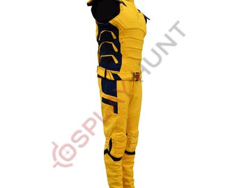 May include: A yellow and navy blue sleeveless jumpsuit featuring a high collar, shoulder pads, and a matching belt with a red and black buckle. The garment includes molded padding on the chest, sides, and knees, with the text COSPLAYHUNT visible.
