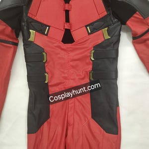 Pu&ograve; includere: Costume cosplay rosso e nero con dettagli dorati. Il costume presenta un tessuto rosso strutturato con pannelli neri su spalle, braccia e busto. Il testo "cosplayhunt.com" &egrave; visibile.