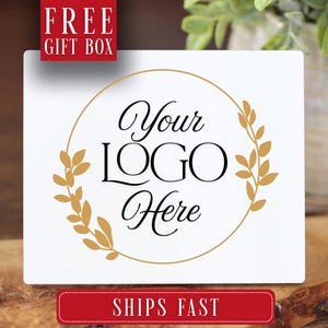 May include: White square with a gold laurel wreath design and the text "Your LOGO Here". The image also includes the text "FREE GIFT BOX" and "SHIPS FAST" in red boxes. The background is blurred.
