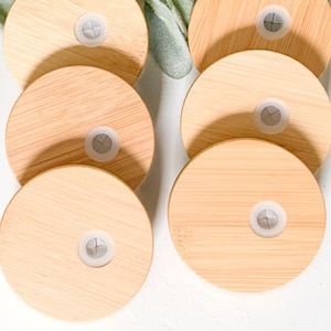 Puede incluir: Una colecci&oacute;n de tapas redondas de bamb&uacute; de color claro con un peque&ntilde;o tap&oacute;n de pl&aacute;stico blanco en el centro. Las tapas est&aacute;n dispuestas en un patr&oacute;n circular, con algunas superpuestas. El bamb&uacute; tiene una veta de madera natural.