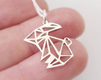 May include: A silver origami rabbit necklace with a small heart detail. The necklace is on a silver chain.