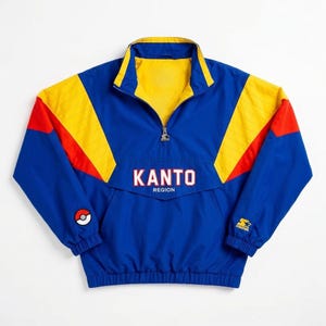 Könnte beinhalten: Blau-gelb-rote Kanto Region Jacke mit halbem Reißverschluss. Die Jacke hat eine Vordertasche und den Text "KANTO REGION" in Weiß. Ein Starter-Logo befindet sich auf dem Ärmel und ein Pokeball-Patch auf dem anderen Ärmel.