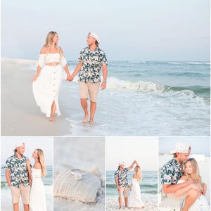 May include: A couple in white clothing walks on a sandy beach with blue water and white waves. The man is wearing a floral patterned shirt and a white baseball cap. The woman is wearing a white dress with a white top.