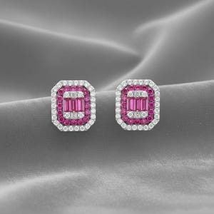 Könnte beinhalten: Ein Paar rechteckige Ohrstecker. Jeder Ohrring hat eine zentrale Anordnung aus rosa Edelsteinen, umgeben von einer Bordüre aus kleineren rosa Steinen und einem äußeren Rahmen aus weißen Edelsteinen. Die Ohrringe sind vor einem grauen Hintergrund platziert.