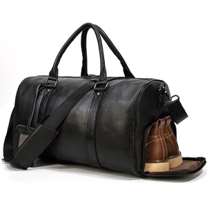 Pu&ograve; includere: Una borsa da viaggio in pelle nera con una lunga tracolla e una tasca con cerniera sul lato. La borsa &egrave; foderata in pelle marrone e ha uno scomparto con cerniera per le scarpe.