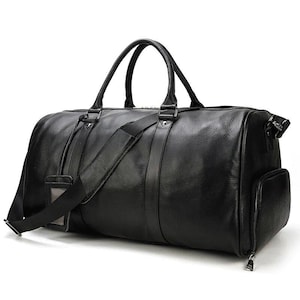 Pu&ograve; includere: Una borsa da viaggio in pelle nera con manico superiore e tracolla. La borsa ha una chiusura con cerniera e una tasca frontale.