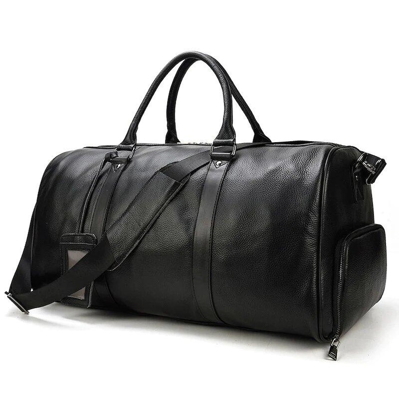 Pu&ograve; includere: Una borsa da viaggio in pelle nera con manico superiore e tracolla. La borsa ha una chiusura con cerniera e una tasca frontale.