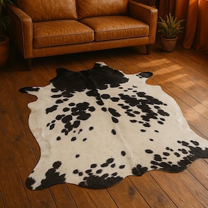 May include: A black and white cowhide rug with a brown leather sofa in the background.