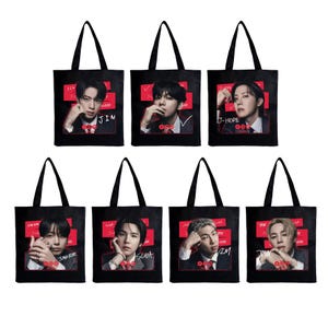 Puede incluir: Bolsas de mano negras con retratos de siete personas, cada una con un nombre impreso debajo. Los retratos están sobre un fondo rojo con texto blanco. Las bolsas tienen asas negras y probablemente son de tela.