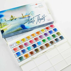 May include: A watercolor paint set with the words "White Nights" on the box. The box features a watercolor painting of a cityscape. Inside, the set contains 36 watercolor paint tubes in various colors, arranged in a white plastic palette.