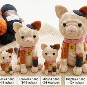 May include: A selection of crochet cat figures in different sizes, from a keychain to a large display piece. The cats are cream-coloured with orange and black accents, wearing pink collars. Yarn skeins in cream, orange, black, pink, yellow, and green are also present.