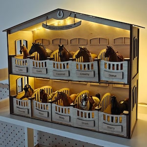 May include: A two-story wooden horse stable with miniature horse figurines in each stall. The stable has a sign that reads "Michael's Dream Stable" and is illuminated with small lights. Each stall is labeled with a horse's name.