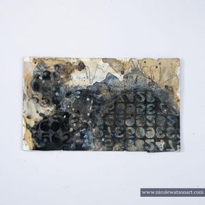 May include: Abstract mixed media artwork on paper. The piece features a collage of textures, including dark gray and black ink splatters, and a grid of numbers. The background has a vintage, aged appearance with tan and brown tones.