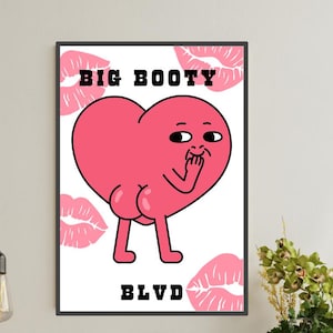 Op de afbeelding: Een ingelijste kunstdruk met een roze hartkarakter met een kont, knipogend en zijn hand omhoog houdend. De woorden "BIG BOOTY" en "BLVD" staan boven en onder het hart. Roze lipafdrukken omringen het hart op een witte achtergrond.