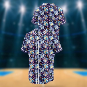Puede incluir: Dos camisas de béisbol azul marino de manga corta. Las camisas presentan un patrón repetido de personajes de dibujos animados azules, corazones y estrellas. Tienen ribetes blancos a lo largo del cuello, las mangas y la botonadura.