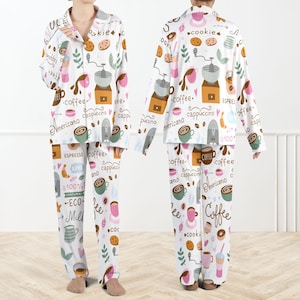 May include: White pajama set with a coffee-themed print. The long-sleeved top and pants feature coffee cups, coffee grinders, cookies, and text like "coffee," "cappuccino," and "espresso." The set includes a button-down top and drawstring pants.