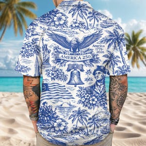 May include: White and blue button-down shirt with a patriotic design. The shirt features illustrations of the American flag, the Statue of Liberty, an eagle, and the Liberty Bell. The text "America 250" is also visible on the shirt.