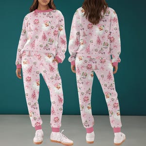 May include: A matching pink pajama set featuring a festive Christmas pattern. The long-sleeved top and pants are adorned with Santa Claus, Christmas trees, and floral designs. The set has pink cuffs and trim.