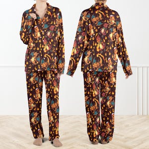 May include: Brown pajama set featuring a repeating pattern of orange and yellow cartoon characters with flames. The long-sleeved top has a button-down collar, and the pants have a relaxed fit. The pajamas are made of a soft, comfortable material.