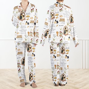 May include: White pajama set with a repeating pattern of framed illustrations, butterflies, roses, and text. The text includes phrases like "I love you" and "We are all fools in love." The set includes a collared button-down shirt and matching pants.