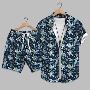 May include: Navy blue matching shirt and shorts set. The set features a repeating pattern of light blue and yellow mythical creatures and aquatic plants. The shirt is short-sleeved and open, revealing a white undershirt. The shorts have a white drawstring.