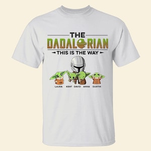May include: White t-shirt featuring the text "THE DADALORIAN THIS IS THE WAY" above an illustration of a Mandalorian helmet and four Grogu characters. The names Laura, Kent, David, Anna, and Dustin are below the Grogu characters.