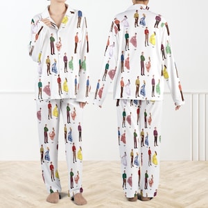 Può includere: Completo pigiama bianco con un motivo ripetuto di figure colorate in vari outfit. La parte superiore a maniche lunghe ha un'abbottonatura frontale e un colletto. I pantaloni hanno una vestibilità ampia. Le figure sono in tonalità di rosso, verde, blu, giallo e marrone.