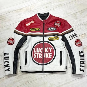Puede incluir: Chaqueta de moto de cuero blanco, rojo y negro con múltiples parches y el texto "LUCKY STRIKE" en la parte delantera y las mangas. La chaqueta tiene cuello alto y cremallera frontal. Los parches incluyen "MOTUL", "MICHELIN" y "ARAI".