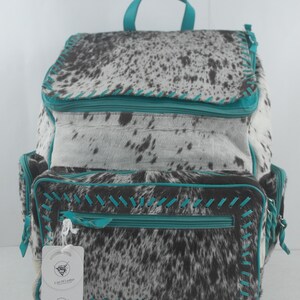 May include: A turquoise and white cowhide backpack with a zippered pocket and a tag that reads "L'art Du Leather # 35".