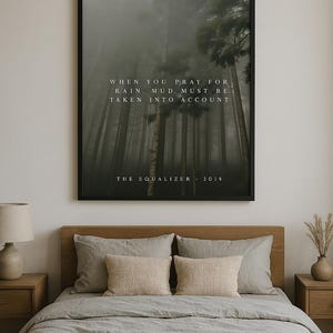 Puede incluir: Una impresión enmarcada en negro con una cita sobre la lluvia y el barro. La cita dice "Cuando rezas por la lluvia, el barro debe tenerse en cuenta." La cita se atribuye a "The Equalizer, 2014". La impresión presenta una escena de bosque brumoso.