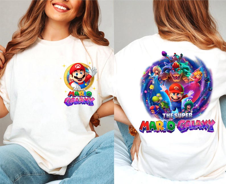 May include: Off-white t-shirt featuring a colorful graphic of Mario from the Super Mario Galaxy video game. The front design shows Mario waving, with the words "Mario Galaxy". The back of the shirt displays a larger, detailed scene with multiple characters and the text "The Super Mario Galaxy".