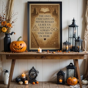 Può includere: Un tavolo rustico in legno decorato per Halloween. Una zucca intagliata, lanterne nere e una stampa incorniciata con il testo "THE ONES THAT LOVE US NEVER REALLY LEAVE US. YOU CAN ALWAYS FIND THEM IN HERE" sono esposti.