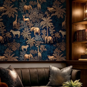 Op de afbeelding: Donkerblauwe behang met een herhalend patroon van gouden bomen en safaridieren zoals olifanten, giraffen en zebra's. Het behang bevindt zich boven een bruine bank met decoratieve kussens.