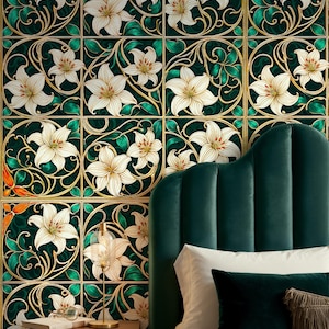 Op de afbeelding: Decoratief behang met een herhalend patroon van witte lelies met gouden accenten en groene bladeren op een donkergroene achtergrond. Het ontwerp doet denken aan de Art Nouveau-stijl. Een donkergroen fluwelen hoofdbord en kussens staan op de voorgrond.