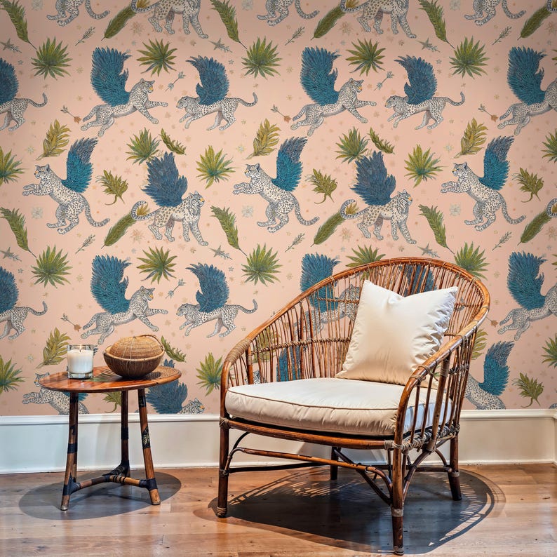 Boho sitting corner with rattan lounge chair and coconut candle framed by Tropical Wallpaper of winged wildcats and leafy botanicals; Boho Wallpaper peel-and-stick mural brings whimsical jungle energy to a cosy space.